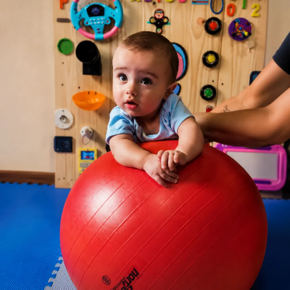 Bebê apoiado na bola de pilates durante atividade de estimulação na Escola Giz de Cera